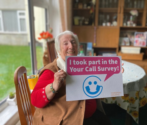 A photo of Mrs Howard, Autumn winner of the Your Call survey, smiling and holding up a board to say I took part in the Your Call survey.