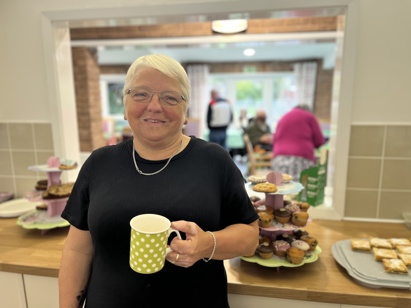 Inclusion officer Babs drinking coffee selling cakes to fund raise for macmillan cancer
