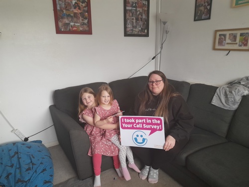 Mrs Margereson with her two daughters in their home. They are holding a sign that says "i took part in the your call survey"