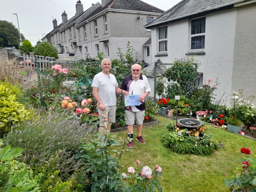 Chair of Tenants Forum John presenting Colin with a certificate for 1st prize in the garden surrounded by roses